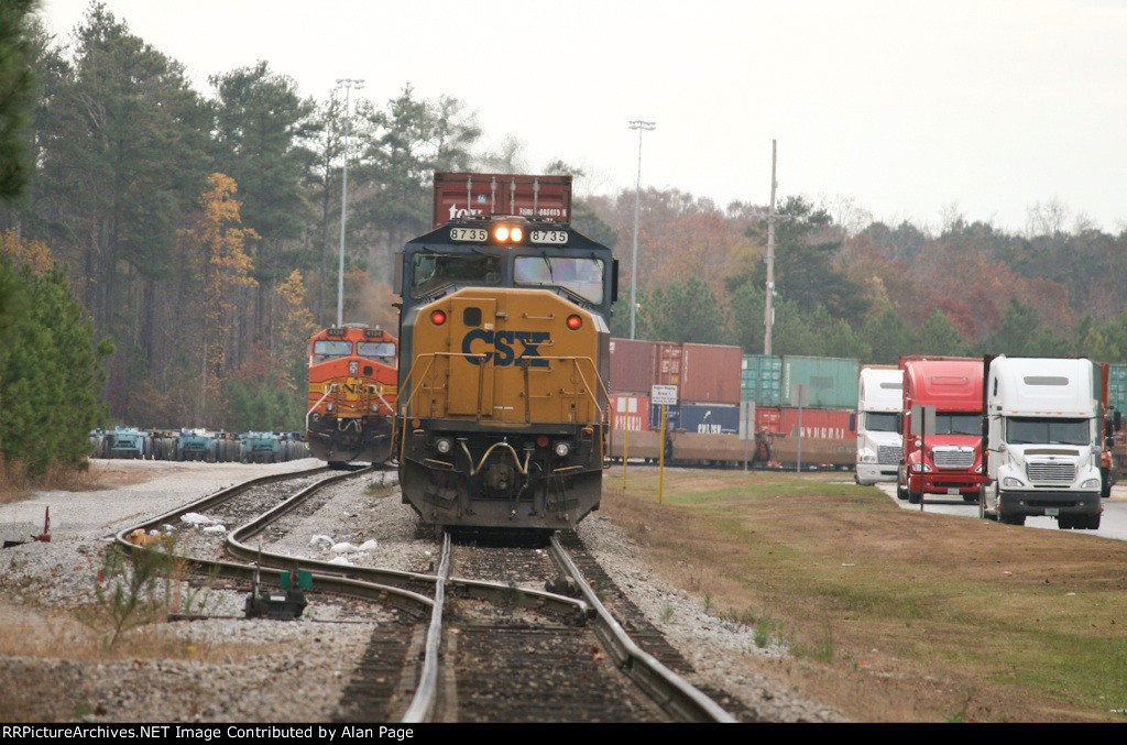 With BNSF 4134 behind, CSX 8735 leads a line of containers